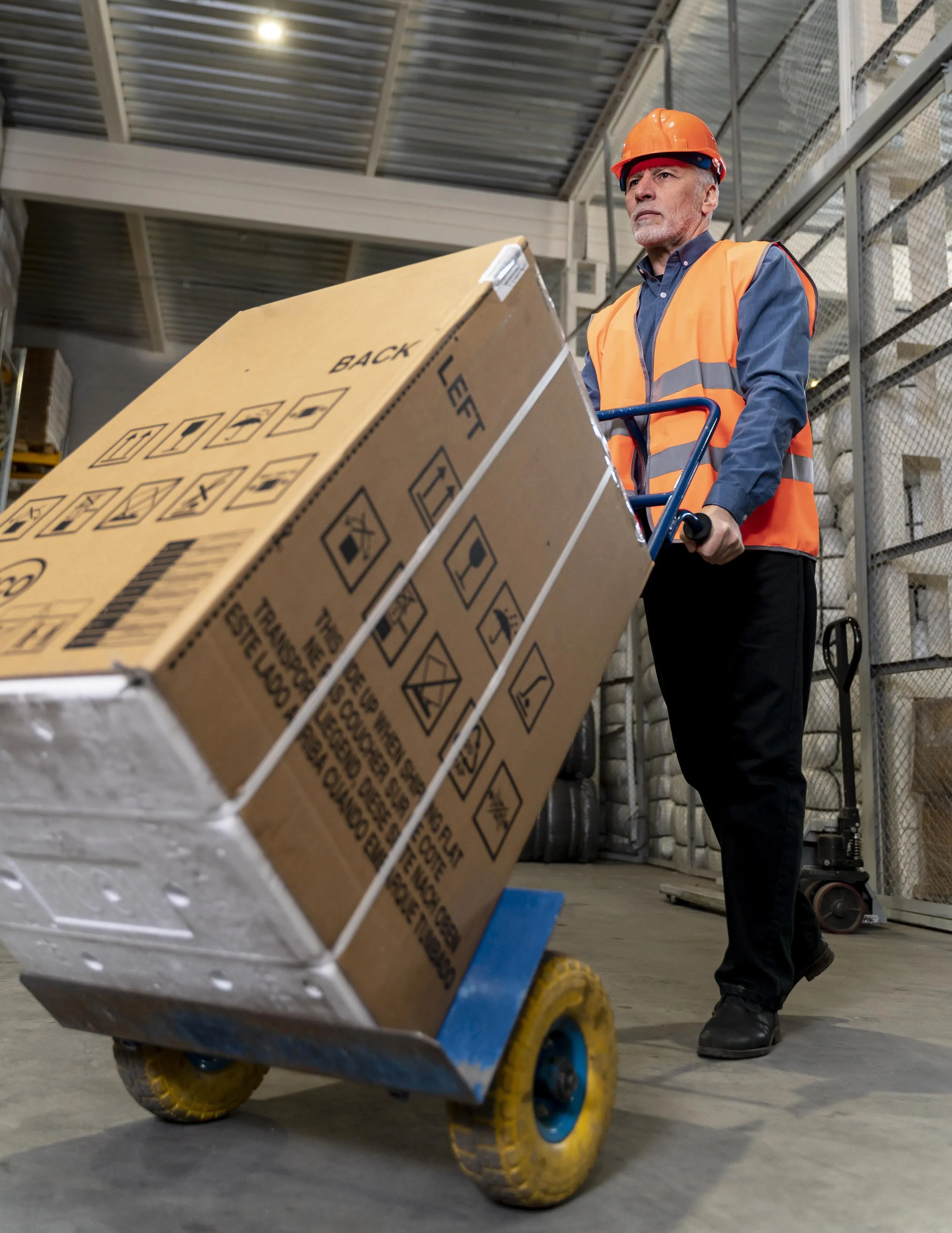 Una persona con un troco de carga que lleva unas cajas.