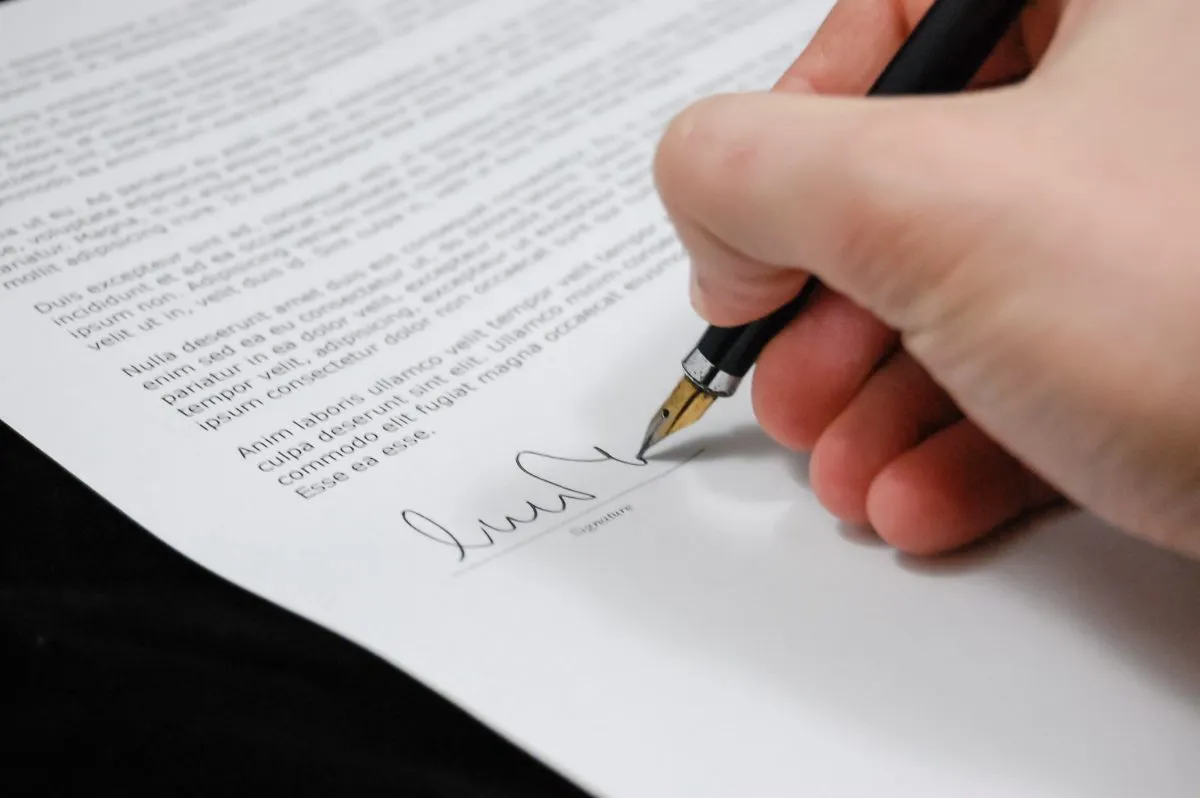 Una mano de una persona firmando un documento legal.
